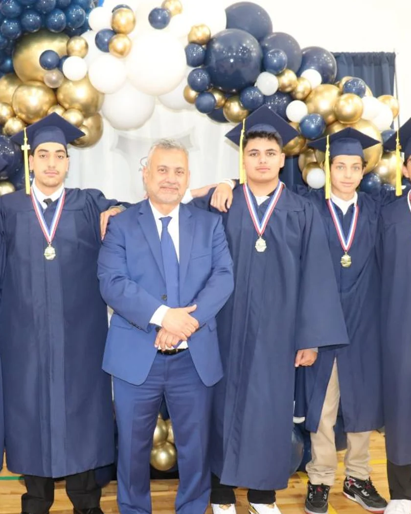 Grade 8 graduates in caps and gowns with the principal