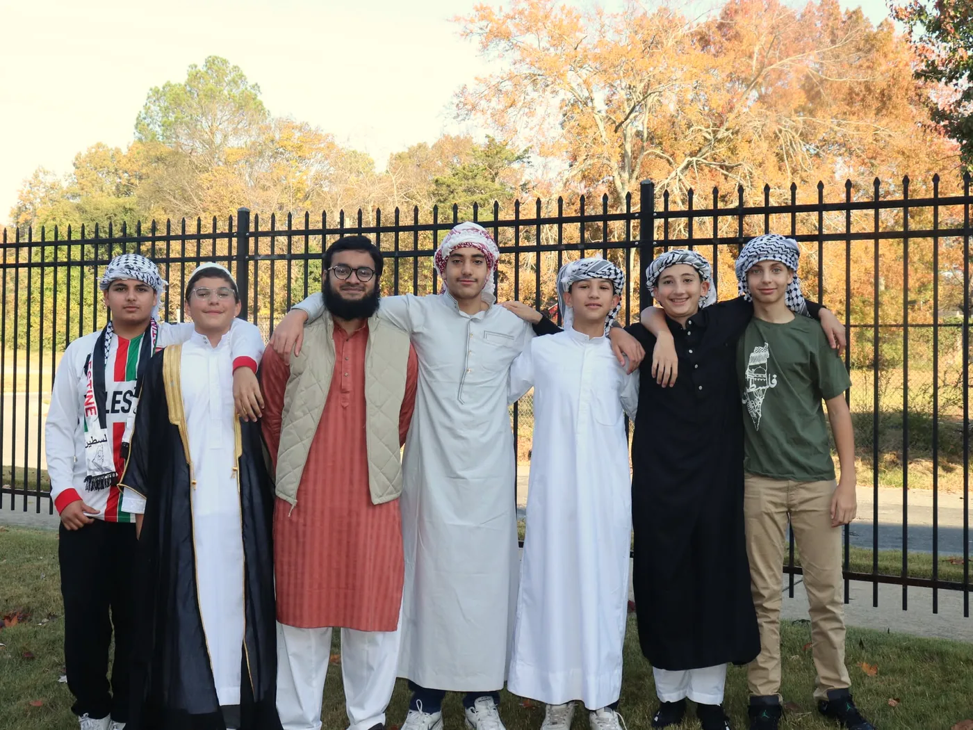 Students standing together outdoors in thobes and keffiyehs